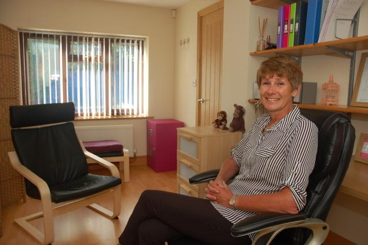 Female Hypnotherapist sitting in office next to a leather chair